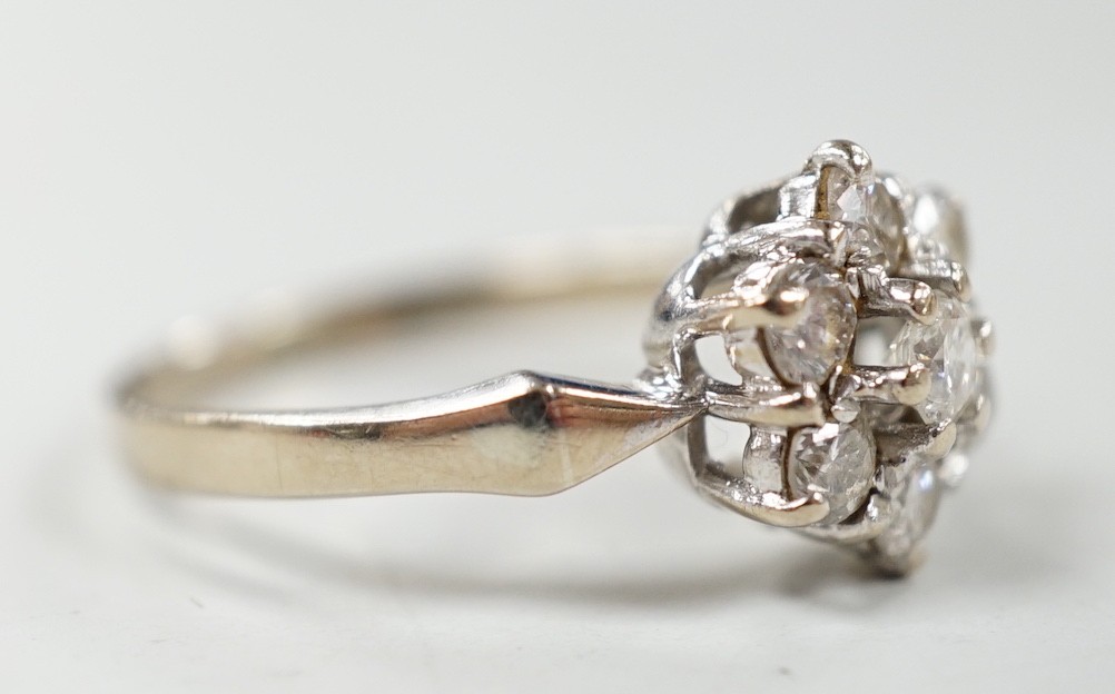 A modern 18ct white gold and seven stone diamond set hexagonal cluster ring, size O, gross weight 3.9 grams.